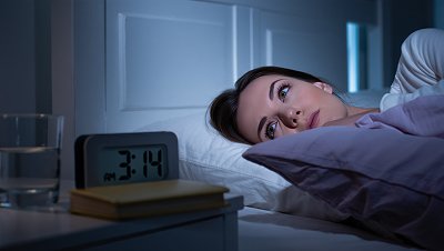 Девушка лежит в кровати и смотрит на часы